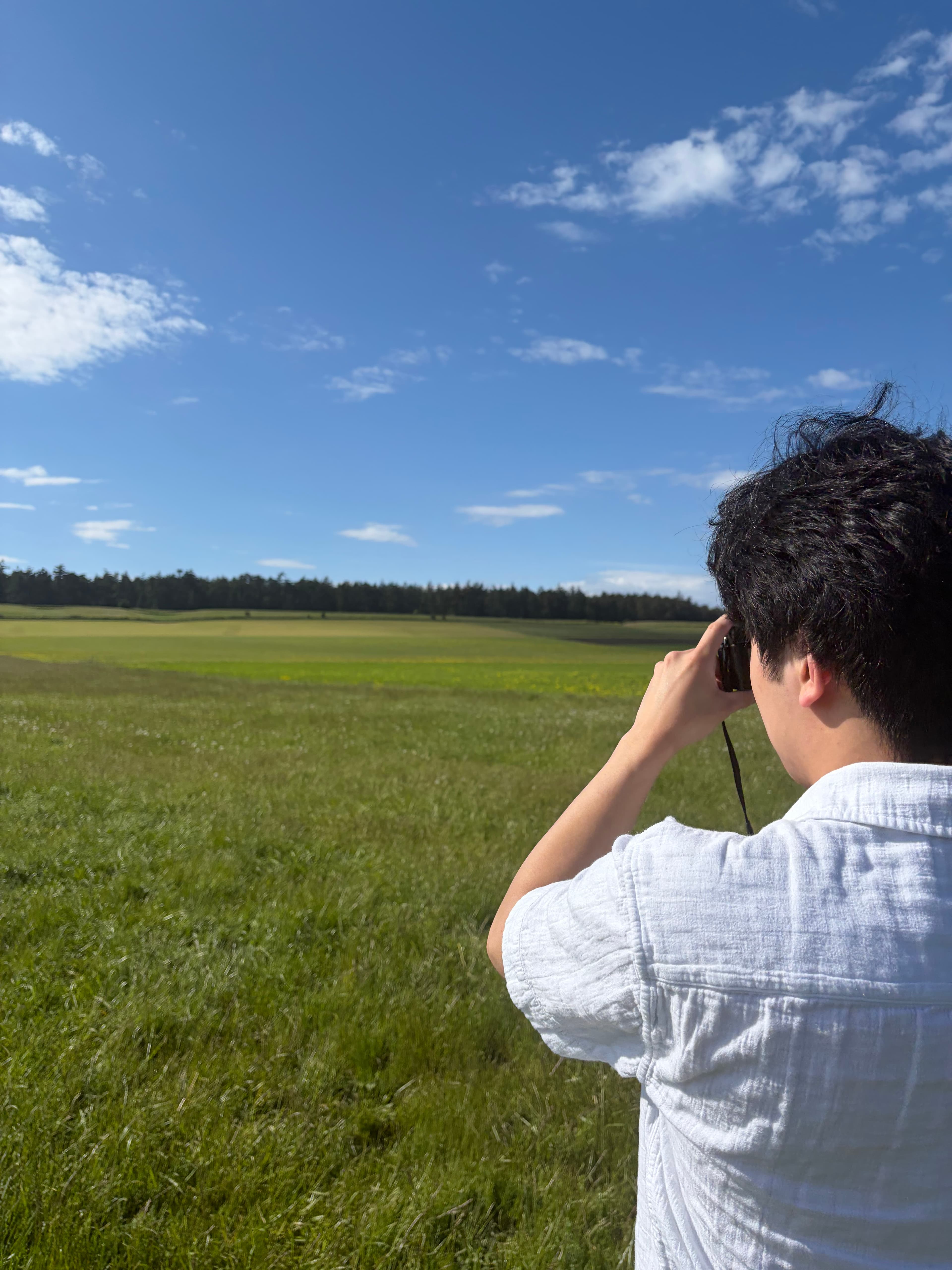 Ethan photographing a grassy field under a blue sky